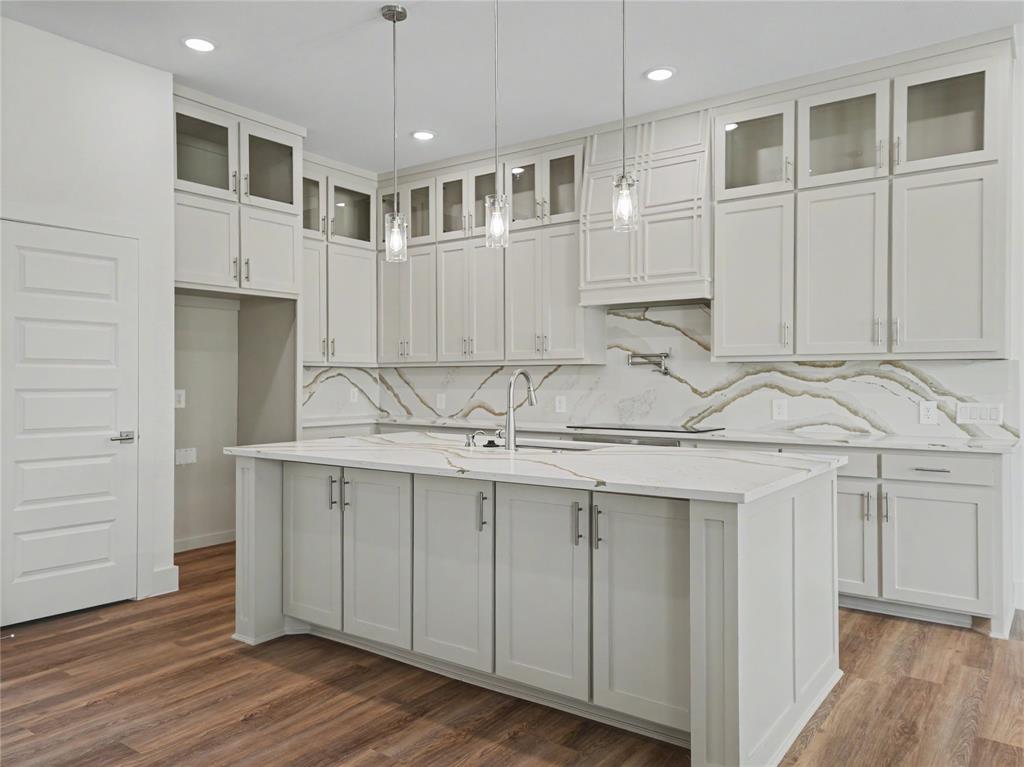 328 Slimp Bluff Azle, TX 76020 - Photo 9 of 30 Kitchen featuring light-toned cabinetry, a spacious island with a sink, elegant pendant lighting, a patterned backsplash, and wood-finish flooring