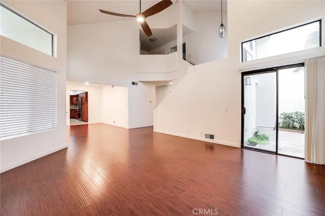 a view of a big room with wooden floor and windows