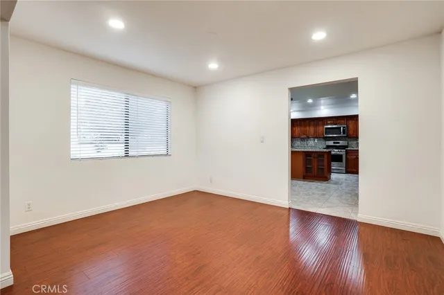 an empty room with wooden floor and kitchen