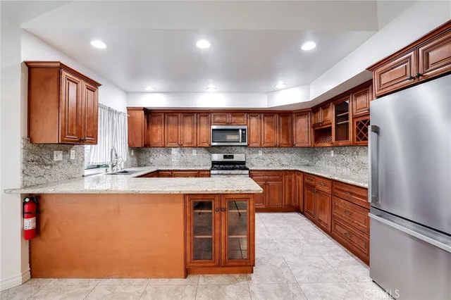 a kitchen with stainless steel appliances granite countertop a stove top oven a sink dishwasher a refrigerator and a microwave