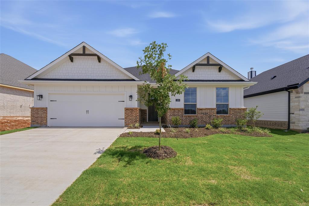 1209 Colca Drive Springtown, TX 76082 - Photo 2 of 24 Single-story residence featuring a two-car garage, partial brick and siding exterior, a concrete driveway, and a landscaped front yard