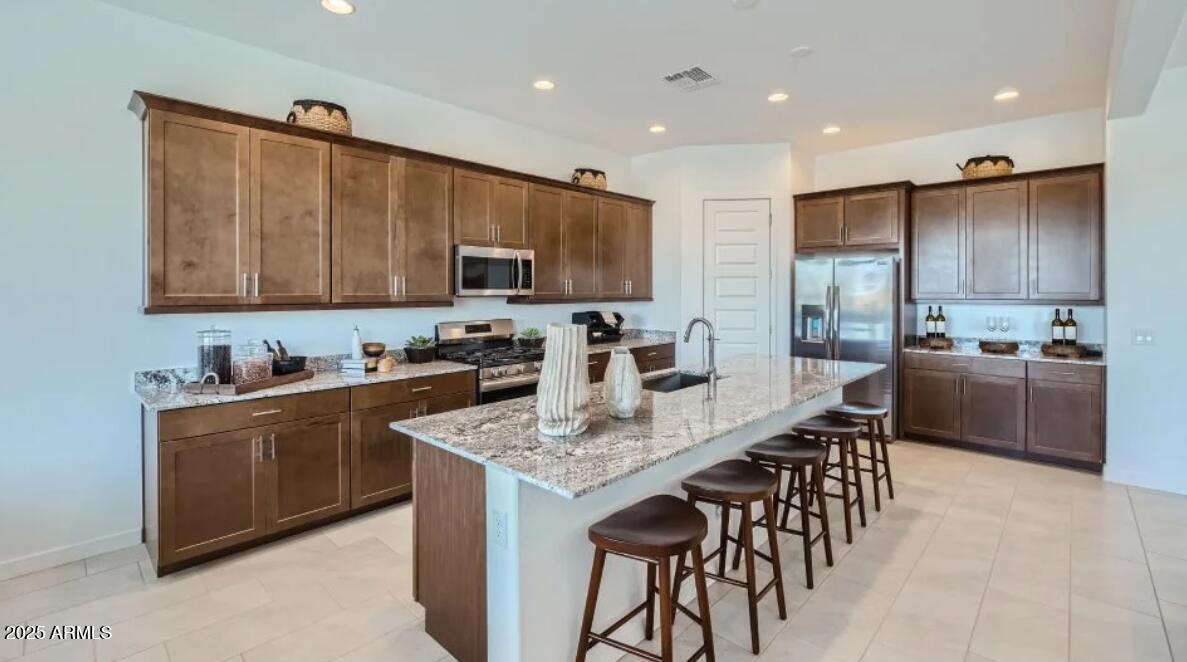 9915 South Dutchman Drive Apache Junction, AZ 85120 - Photo 2 of 27 a kitchen with stainless steel appliances granite countertop a stove top oven a sink dishwasher a refrigerator and a dining table with wooden cabinet