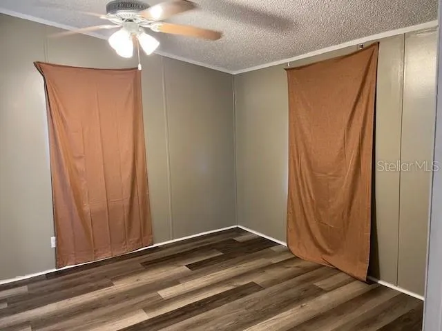 an empty room with wooden floor and fan view