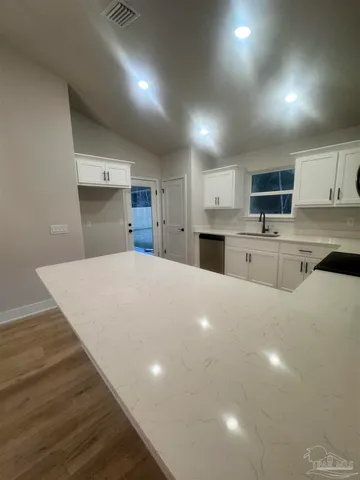 a large white kitchen with kitchen island a sink stainless steel appliances and cabinets