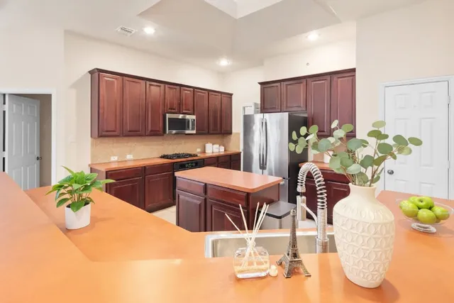 a kitchen with stainless steel appliances kitchen island granite countertop a refrigerator a stove a sink with a dining table and chairs