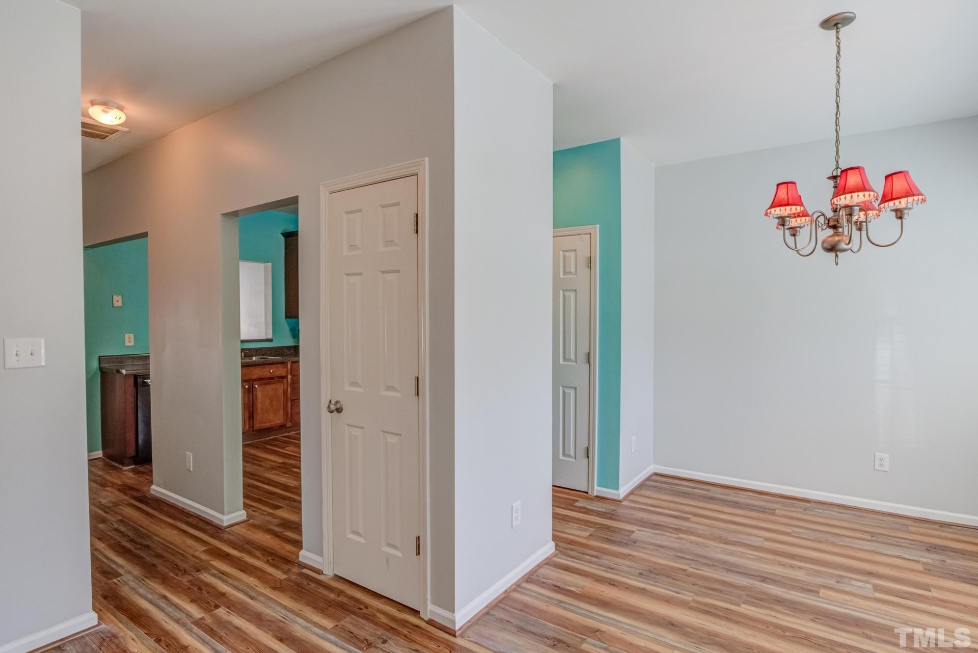 705 Glen Road, Unit 103 Garner, NC 27529 - Photo 4 of 25 a view of a hallway with wooden floor and a chandelier