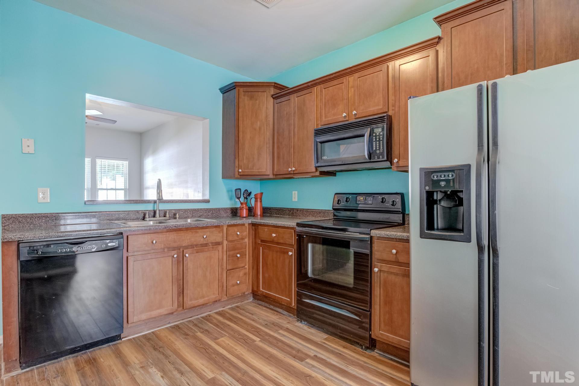 705 Glen Road, Unit 103 Garner, NC 27529 - Photo 8 of 25 a kitchen with stainless steel appliances granite countertop a stove top oven a sink and dishwasher a refrigerator with wooden floor