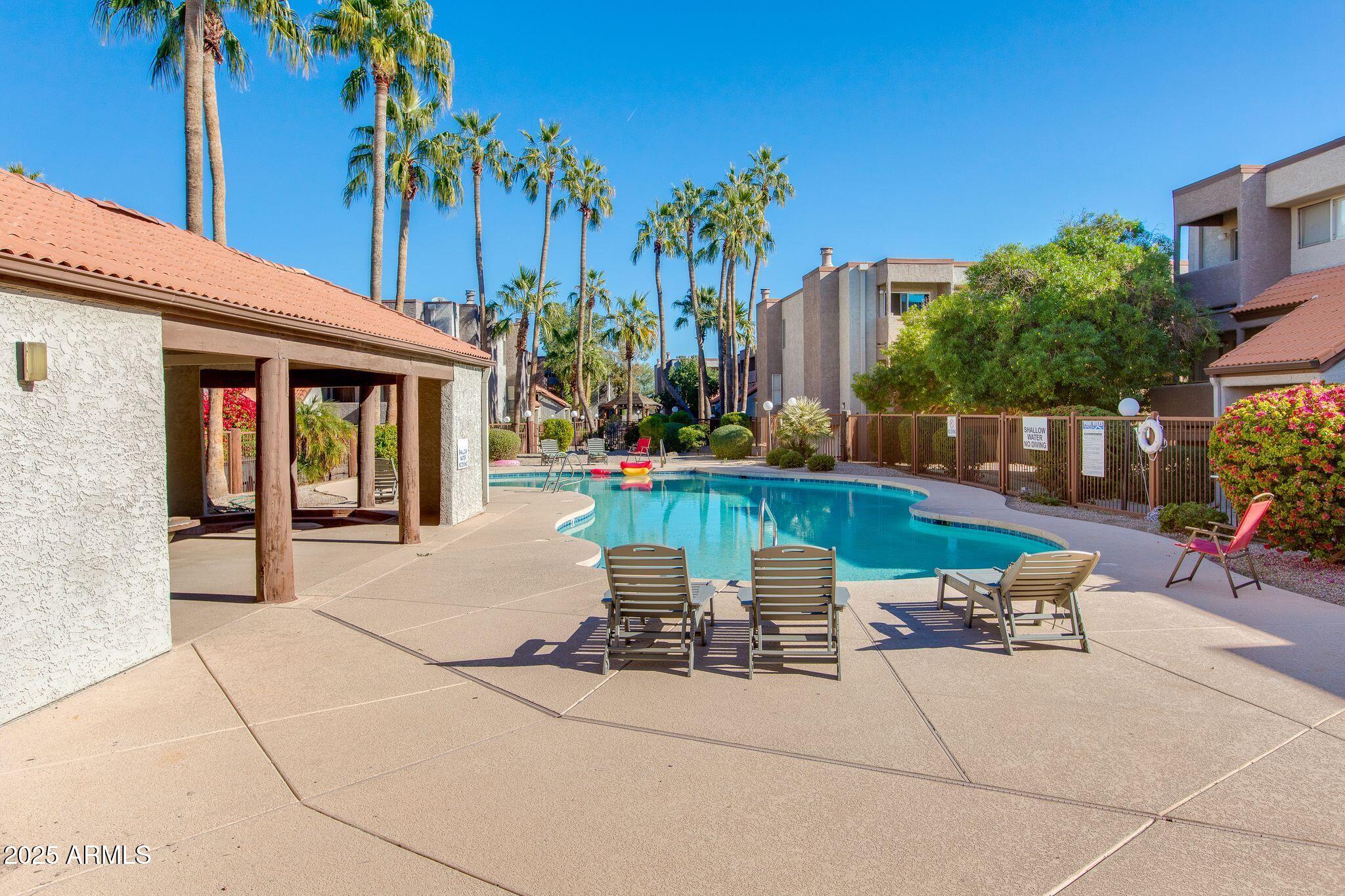 1645 West Baseline Road, Unit 1058 Mesa, AZ 85202 - Photo 41 of 44 a view of a patio with a table and chairs under an umbrella with palm trees