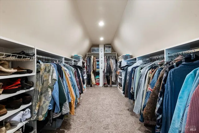 a view of walk in closet with clothes and shoes