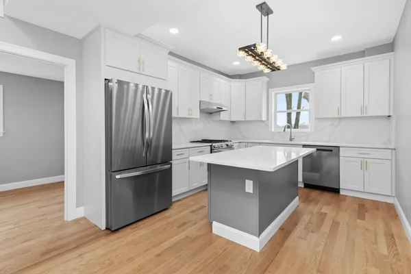 a kitchen with kitchen island granite countertop a sink refrigerator and wooden floor