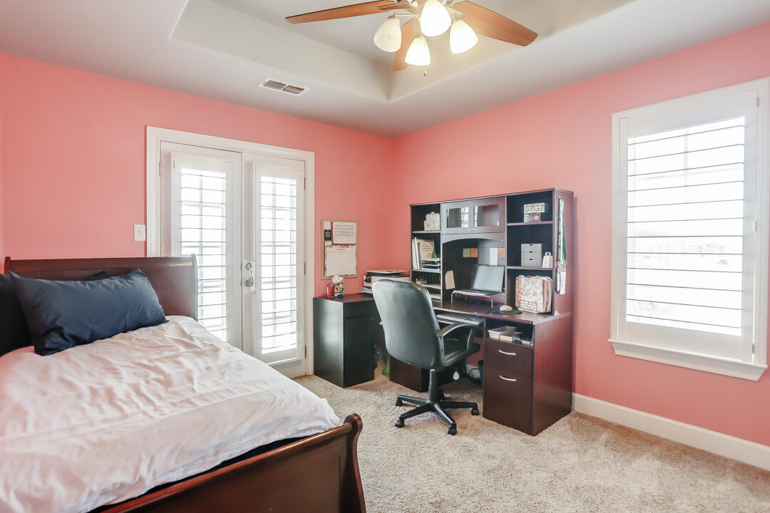 4712 121st Street Lubbock, TX 79424 - Photo 22 of 46 a bedroom with a bed a desk and chair with windows