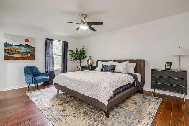 a bedroom with a bed and dresser with wooden floor
