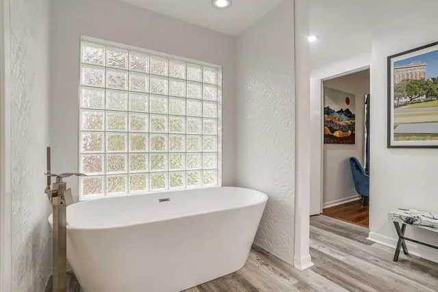 a white bath tub sitting in a bathroom next to a window