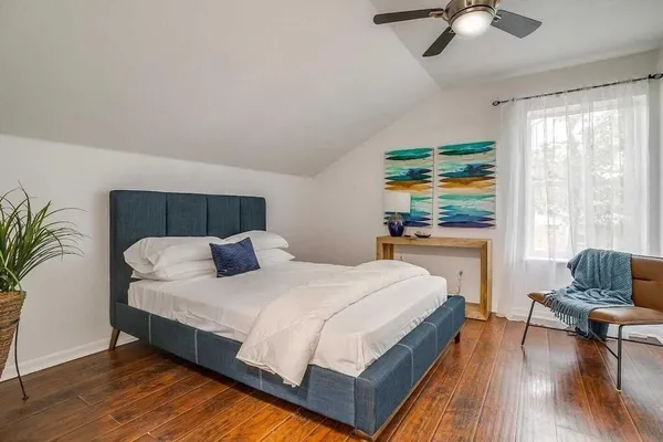 a bedroom with a bed a couch and a flat tv screen on dresser