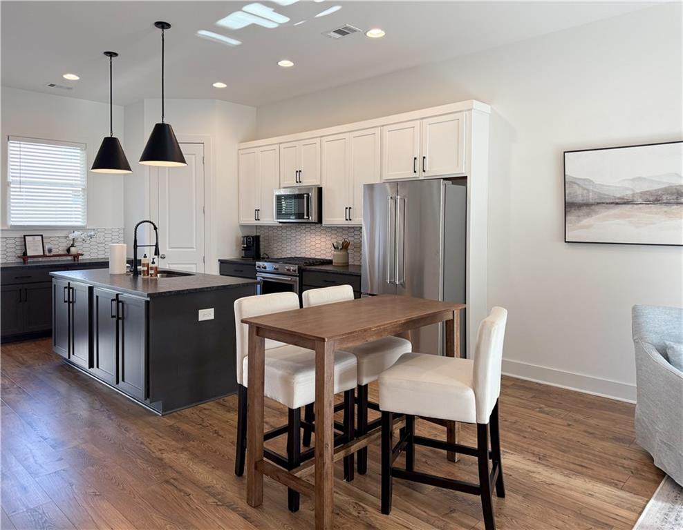 5736 Main Street Flowery Branch, GA 30542 - Photo 12 of 30 a kitchen with stainless steel appliances granite countertop a refrigerator a sink a stove a dining table and chairs