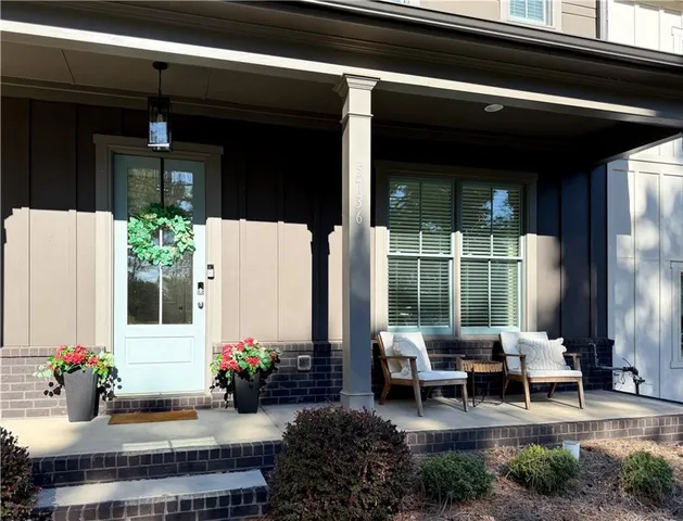 a view of a patio with table and chairs potted plants and floor to ceiling window