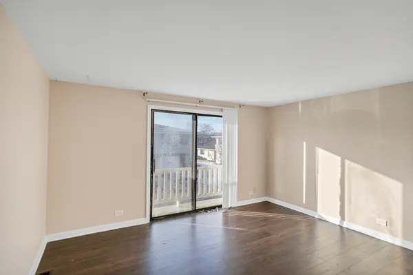 an empty room with wooden floor and windows with curtains