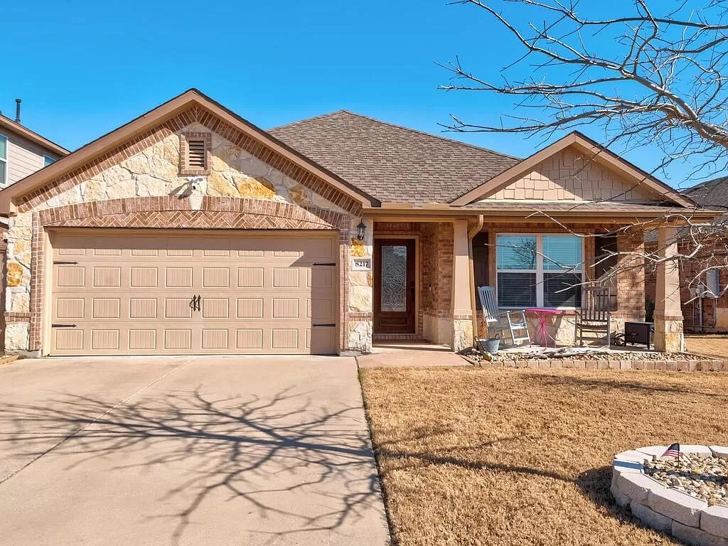 8217 Reggio Street Round Rock, TX 78665 - Photo 1 of 27 View of front facade with covered porch, driveway, a shingled roof, stone siding, and a garage