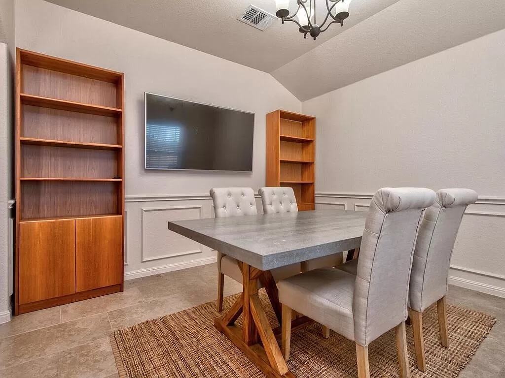 8217 Reggio Street Round Rock, TX 78665 - Photo 13 of 27 Dining space featuring vaulted ceiling, a decorative wall, a wainscoted wall, a chandelier, and a textured ceiling