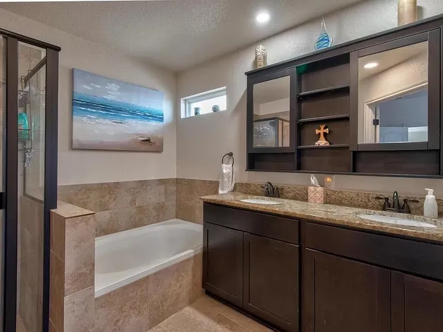 a bathroom with a tub a double vanity sink and mirror