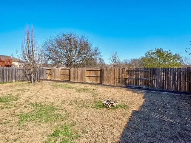 a view of a yard with wooden fence