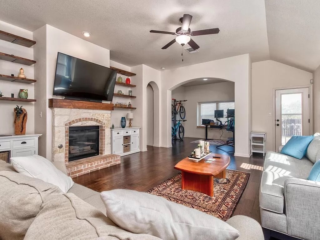 8217 Reggio Street Round Rock, TX 78665 - Photo 5 of 27 Living area with arched walkways, a glass covered fireplace, dark wood finished floors, a textured ceiling, and ceiling fan