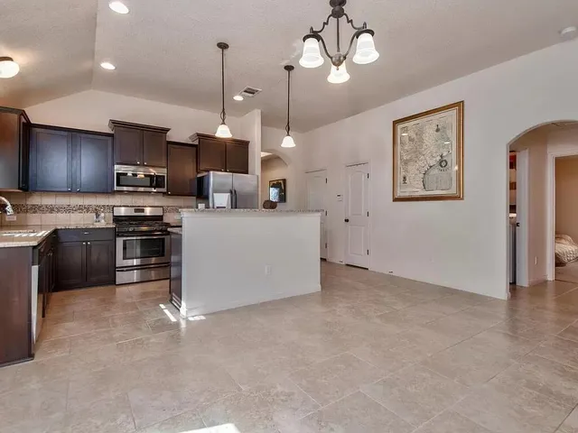 a kitchen with stainless steel appliances granite countertop a stove top oven a refrigerator a sink and a microwave