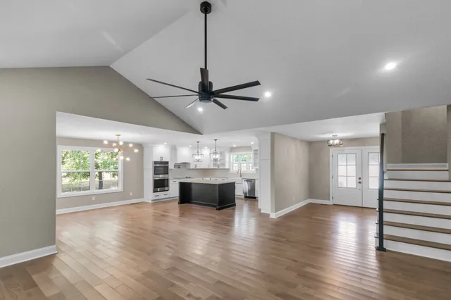 a kitchen with kitchen island granite countertop stainless steel appliances cabinets a sink and a wooden floor
