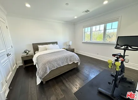 a bedroom with a bed a window and gym equipment