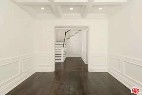 a view of an empty room with wooden floor and stairs