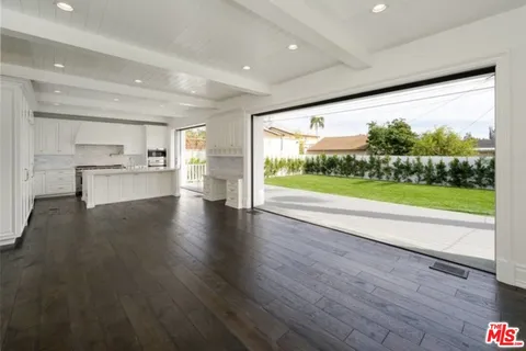 a open kitchen with stainless steel appliances granite countertop a refrigerator a sink dishwasher a stove and white countertops with wooden floor