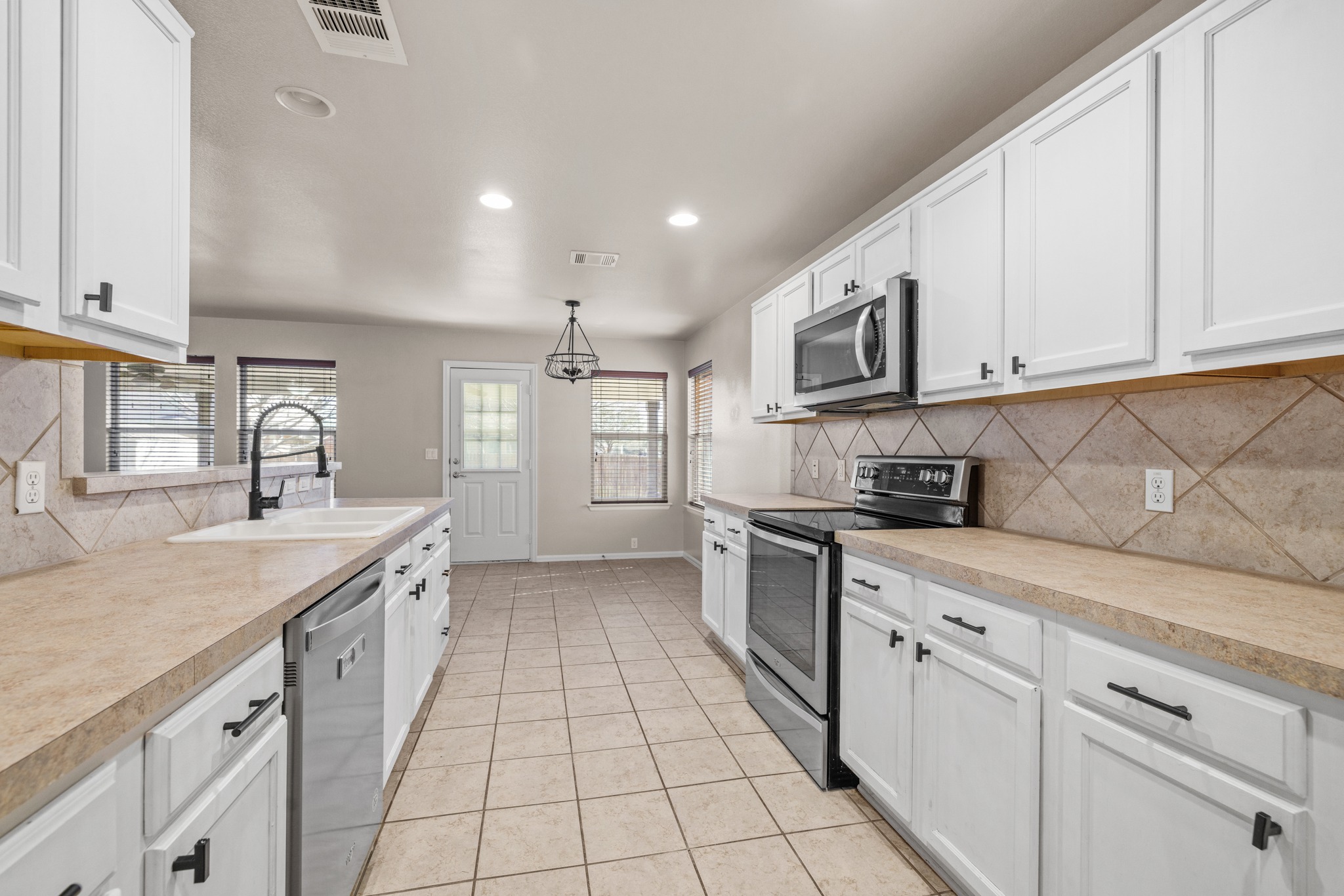 217 Inca Dove Lane Leander, TX 78641 - Photo 12 of 40 a kitchen with stainless steel appliances granite countertop a sink and dishwasher a stove top oven with white cabinets