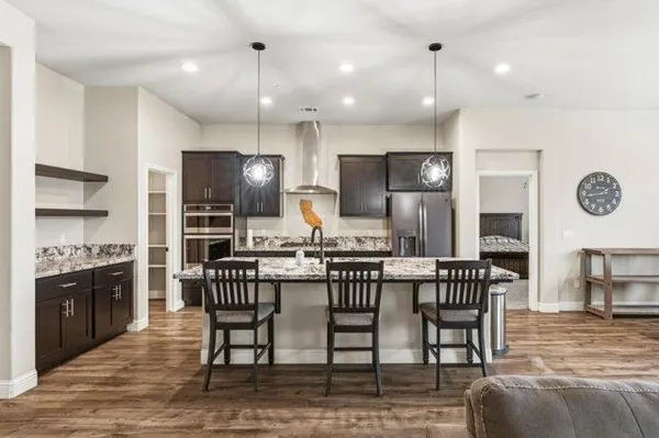 a kitchen with stainless steel appliances kitchen island granite countertop a dining table chairs stove and refrigerator