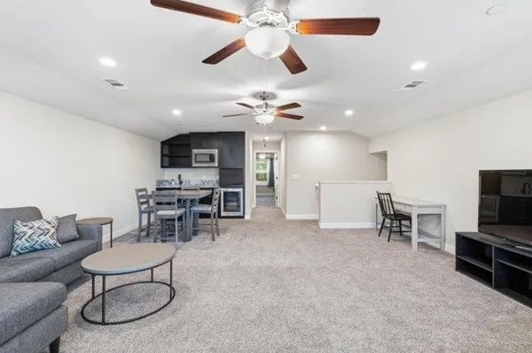 a living room with furniture a dining table and chairs with a ceiling fan