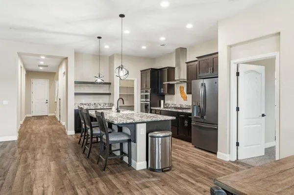 a kitchen with stainless steel appliances kitchen island granite countertop a refrigerator and a stove top oven