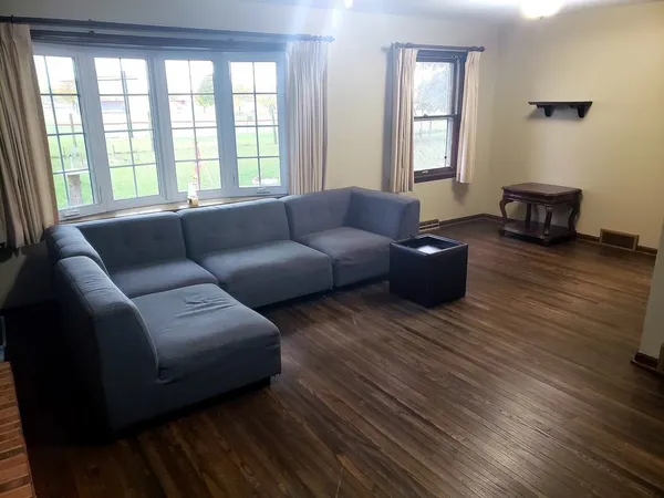 an empty room with wooden floor closet and windows