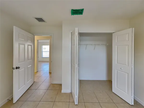 a view of an empty room with closet and a bathroom