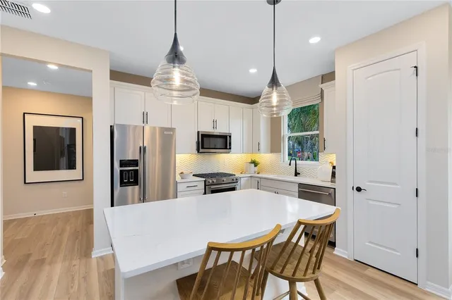 a kitchen with stainless steel appliances a dining table chairs stove refrigerator and microwave