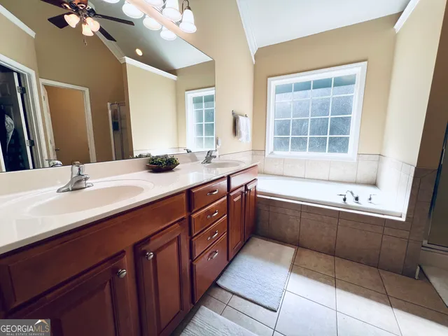 a bathroom with a granite countertop bathtub a double vanity sink a vanity and a large mirror