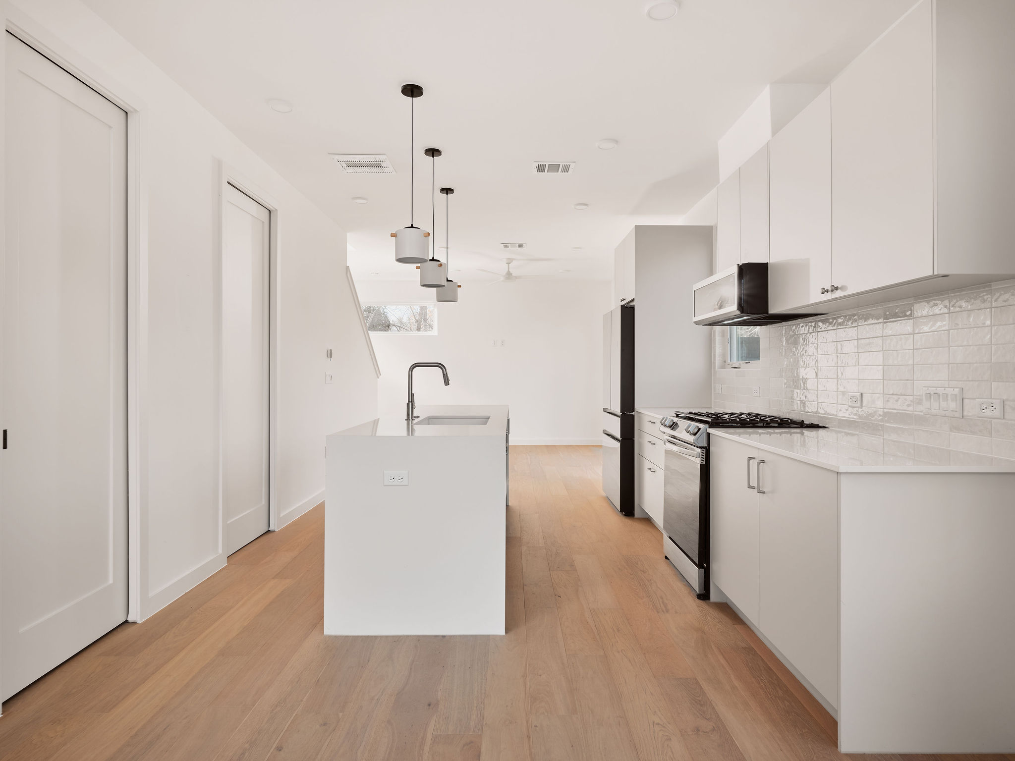 3209 Dolphin Drive, Unit 2 Austin, TX 78704 - Photo 5 of 28 Kitchen featuring hanging light fixtures, gas stove, white cabinets, and modern cabinets