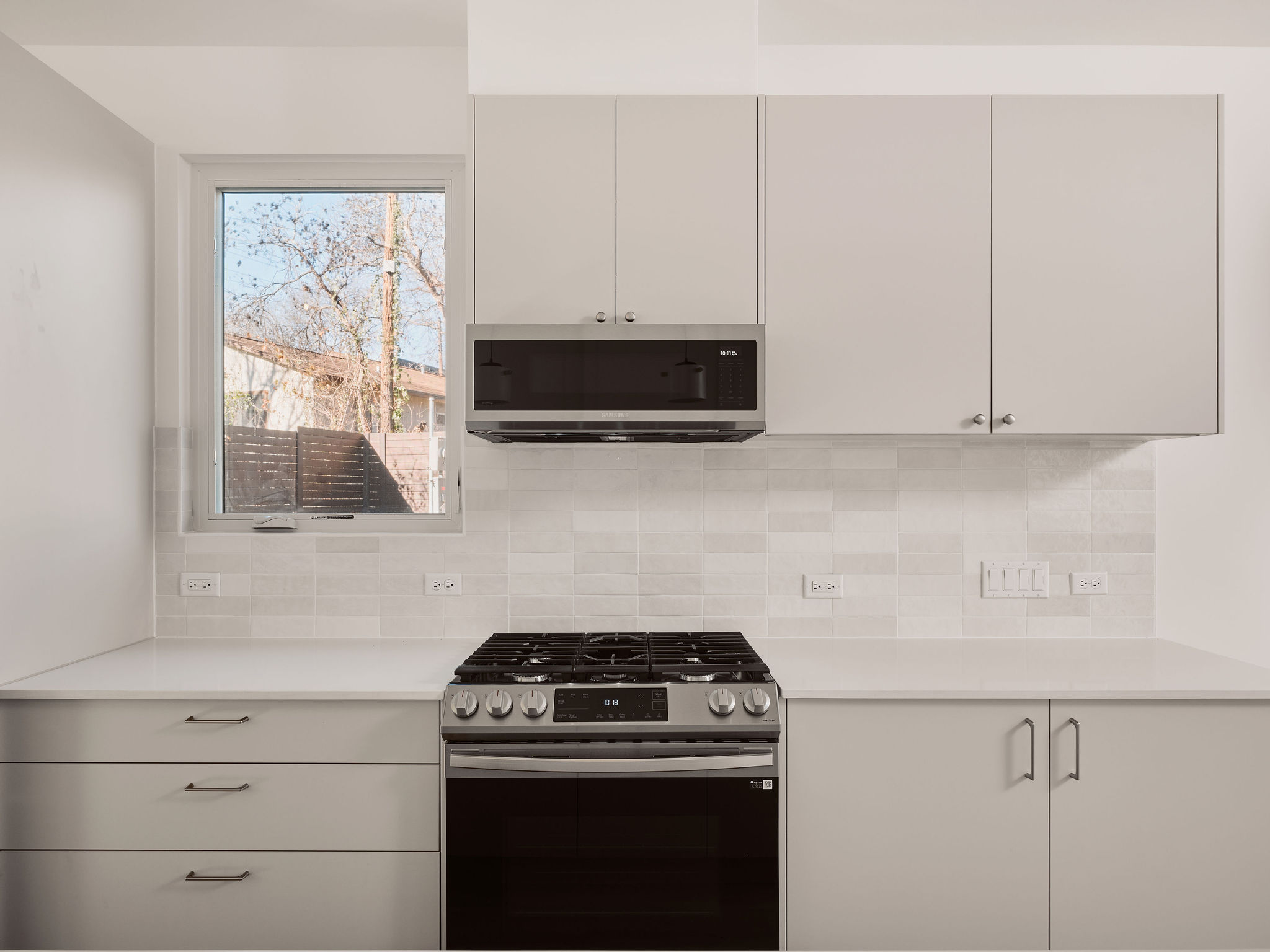 3209 Dolphin Drive, Unit 2 Austin, TX 78704 - Photo 7 of 28 Kitchen featuring appliances with stainless steel finishes, white cabinets, light stone countertops, and tasteful backsplash