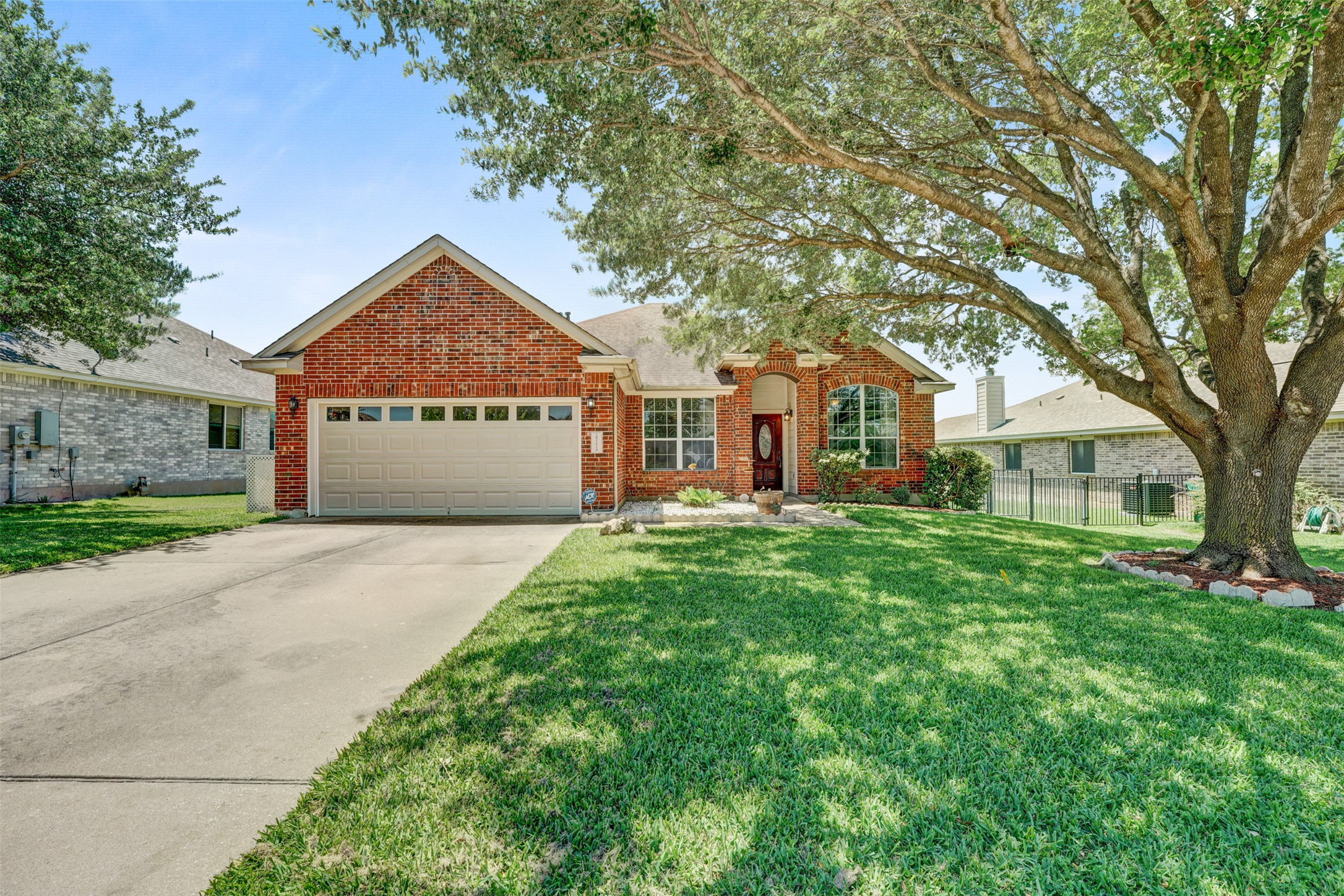 2521 Amen Corner Road Pflugerville, TX 78660 - Photo 3 of 40 Brick facade home featuring an attached two-car garage, concrete driveway, and a mature shade tree