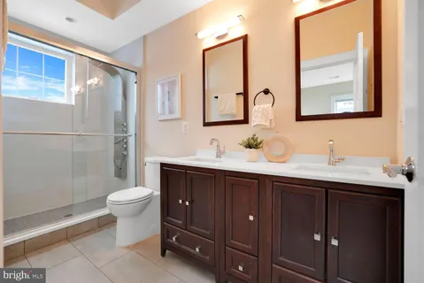 a bathroom with a double vanity sink toilet mirror and shower
