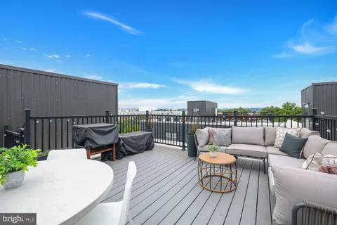 a roof deck with a couches and potted plants with wooden floor