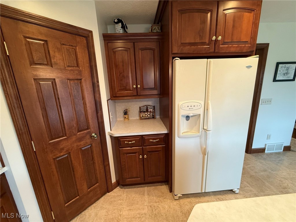 2597 Pyle Road Dover, OH 44622 - Photo 13 of 50 Kitchen featuring white fridge with ice dispenser, light countertops, light tile patterned floors, and backsplash