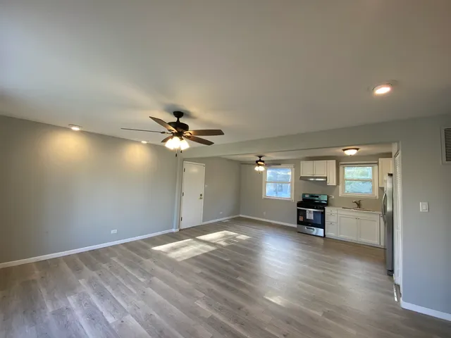 a view of a livingroom with a stove cabinets and wooden floor
