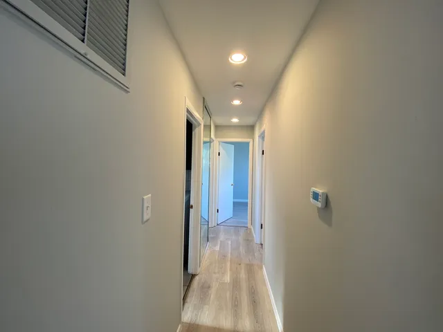 a view of a hallway with wooden floor and a bathroom