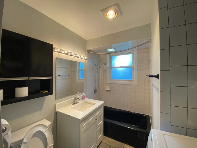 a bathroom with a sink a toilet a mirror and shower