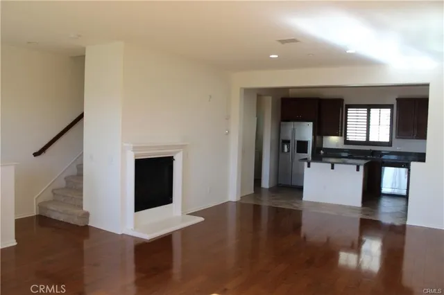 a view of a livingroom with wooden floor and kitchen space with a sink