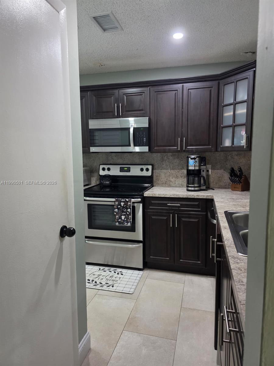 893 Southwest 120th Way Davie, FL 33325 - Photo 8 of 22 a kitchen with a sink a stove and cabinets